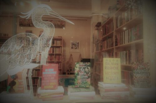 Front window of Heron Books with featured books on display.